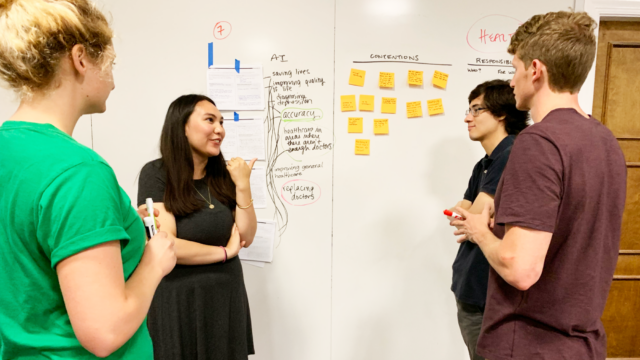Students in the Fall 2019 Introduction to AI course use a white board and sticky notes in an interactive exercise.