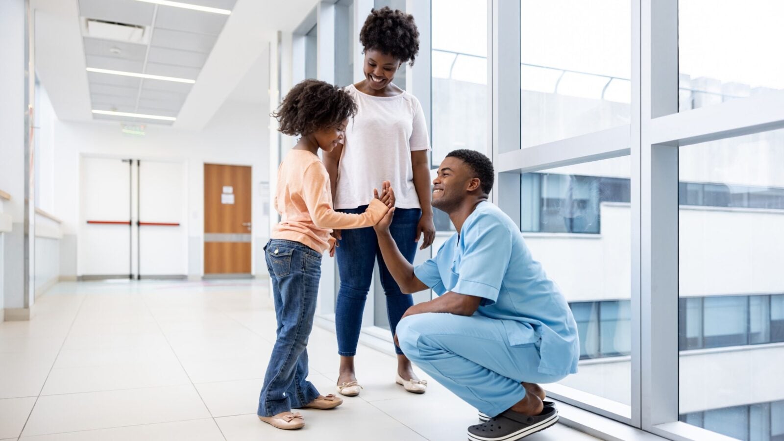 Happy African American girl giving a high-five to a male nurse at the hospital - healthcare and medicine concepts