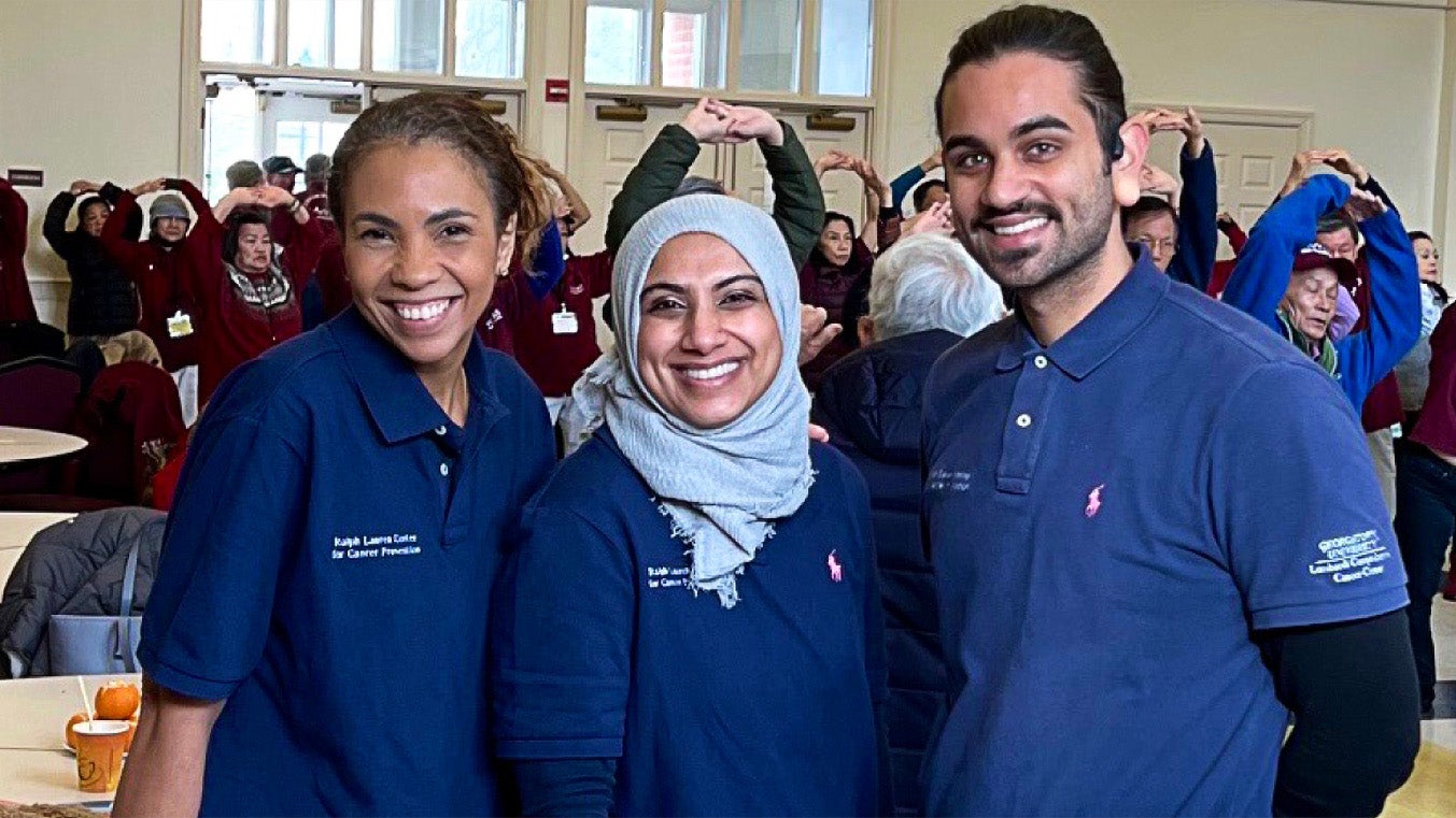 students posing and smiling as people behind them are working out