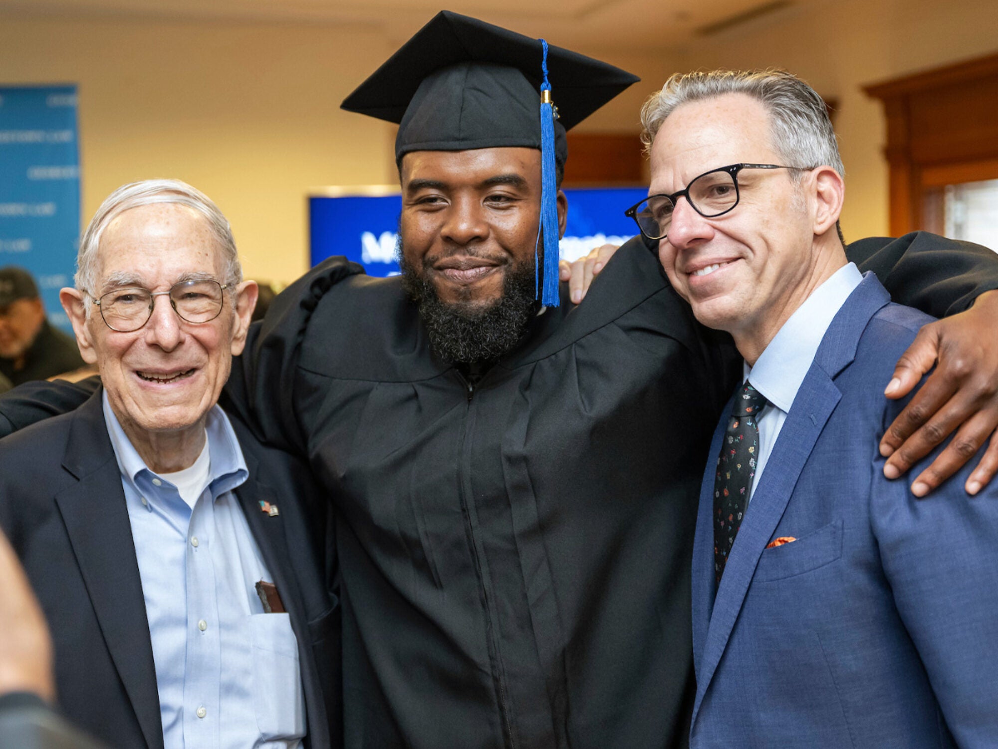 student at graduation posing with professors